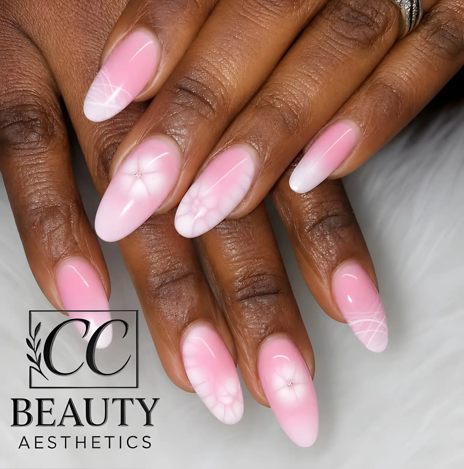 Long almond nails in a pink aura, two with hand-painted white flowers